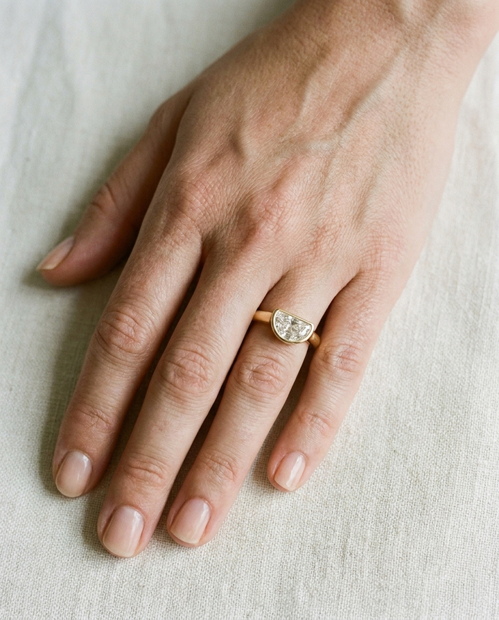 The Agnes Select bezel solitaire half cut engagement ring in 18k yellow gold — top down hand — RockHer
