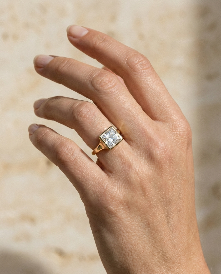 The Agnes Select bezel solitaire princess engagement ring in 18k yellow gold — on hand — RockHer