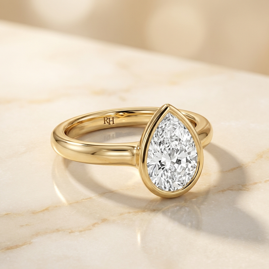The Agnes Select bezel solitaire pear engagement ring in 18k yellow gold — alt-angle hero — RockHer