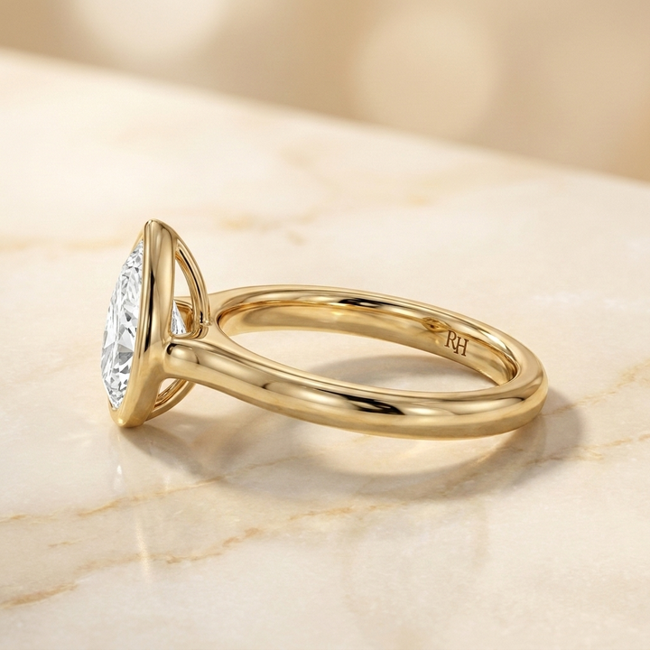 The Agnes Select bezel solitaire pear engagement ring in 18k yellow gold — side profile — RockHer