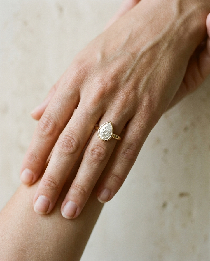 The Agnes Select bezel solitaire pear engagement ring in 18k yellow gold — on hand — RockHer