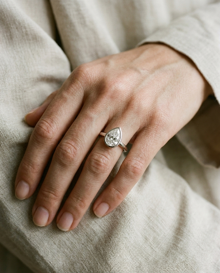 The Agnes Select bezel solitaire pear engagement ring in platinum — on hand — RockHer