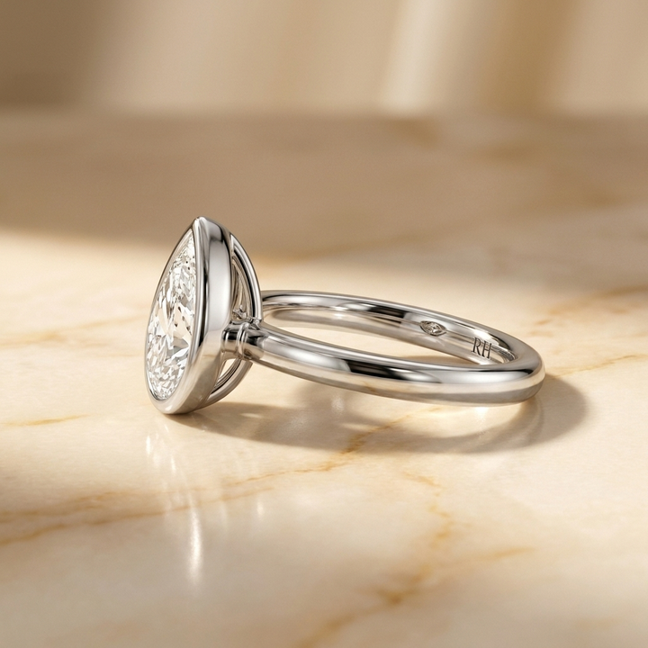 The Agnes Select bezel solitaire pear engagement ring in platinum — side profile — RockHer