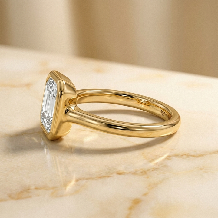 The Agnes Select bezel solitaire square emerald engagement ring in 18k yellow gold — side profile — RockHer