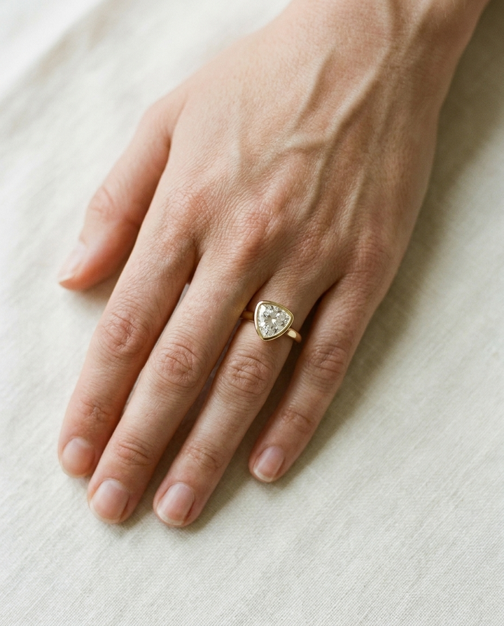 The Agnes Select bezel solitaire shield engagement ring in 18k yellow gold — top down hand — RockHer