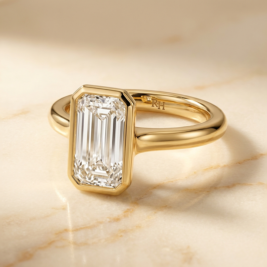 The Agnes Select bezel solitaire tapered baguette engagement ring in 18k yellow gold — alt-angle hero — RockHer