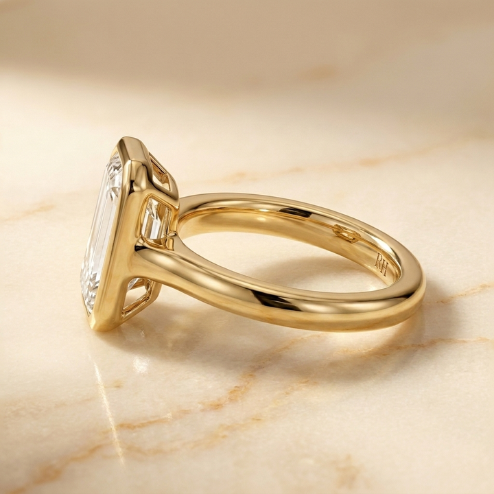 The Agnes Select bezel solitaire tapered baguette engagement ring in 18k yellow gold — side profile — RockHer