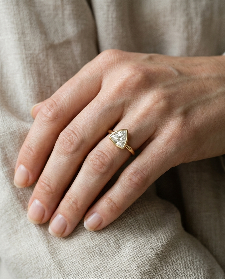 The Agnes Select bezel solitaire trillion engagement ring in 18k yellow gold — on hand — RockHer