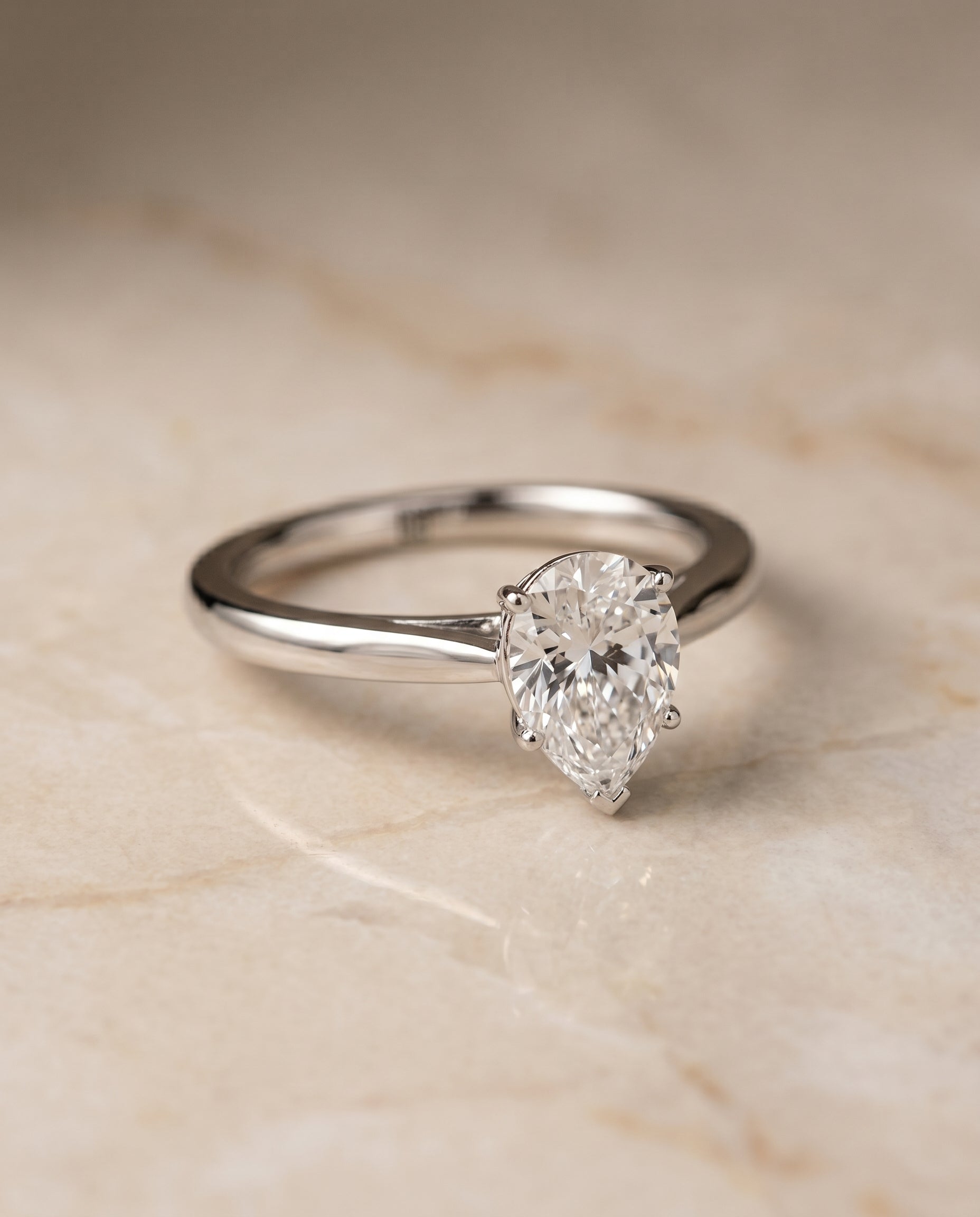 Comfort Fit Secret Stone Solitaire Pear Shape, in Platinum – angled view | RockHer