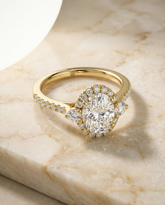 Three Stone Delicate Halo Oval, in 18K Yellow Gold – angled view | RockHer