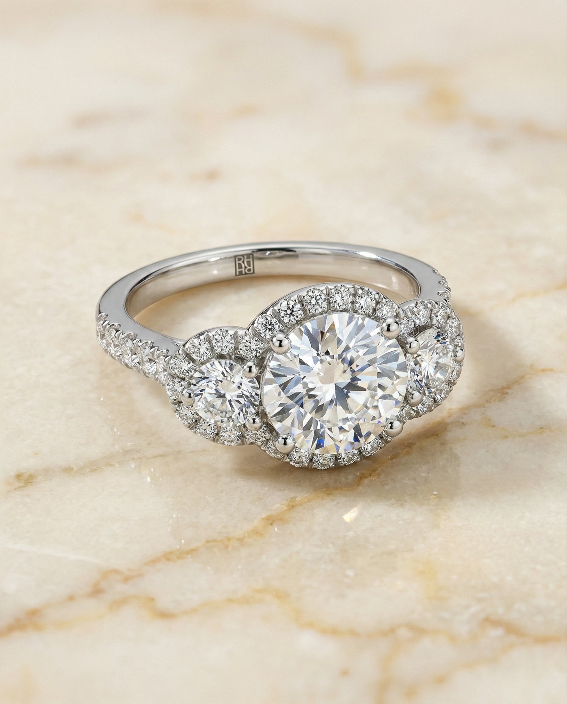 Round Brilliant, Three Stone Halo, in Platinum, pave setting – angled view | RockHer