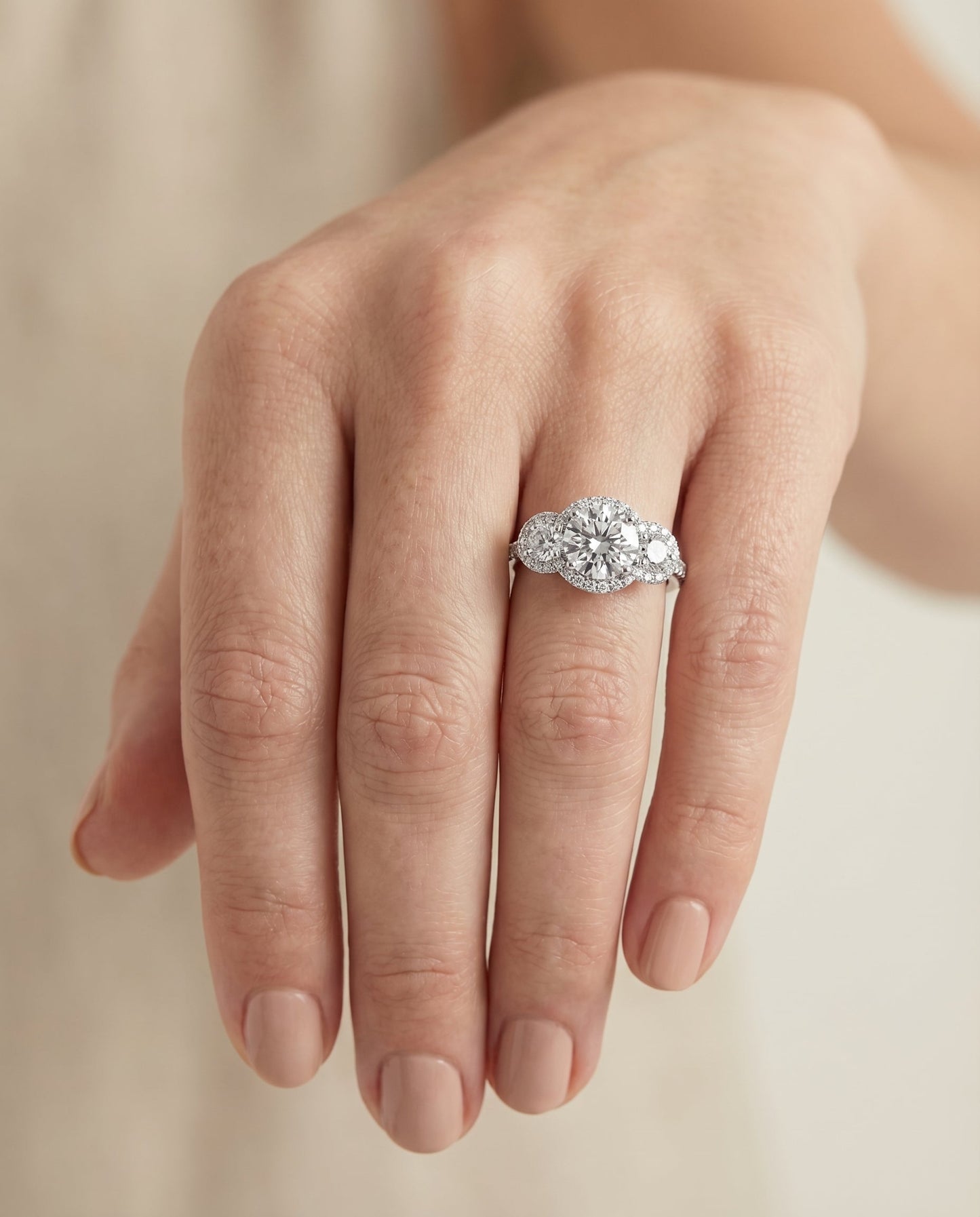 Round Brilliant, Three Stone Halo, in Platinum, pave setting – lifestyle shot | RockHer